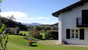 A modern house with a garden, a paved pathway, and a view of mountains in the background. - Appartment Ihi-Toki, sunny garden apartment in a breathtaking location (Saint-Pée-sur-Nivelle)