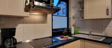A modern kitchen with a built-in microwave, a coffee maker, and a sink.