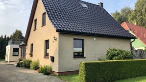 Une maison à deux étages, avec un toit recouvert de tuiles, une petite fenêtre et une boîte aux lettres.
