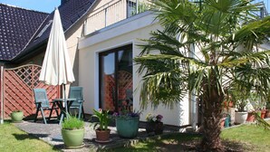 Une maison dotée d’un patio, de meubles d’extérieur et de plantes en pot.