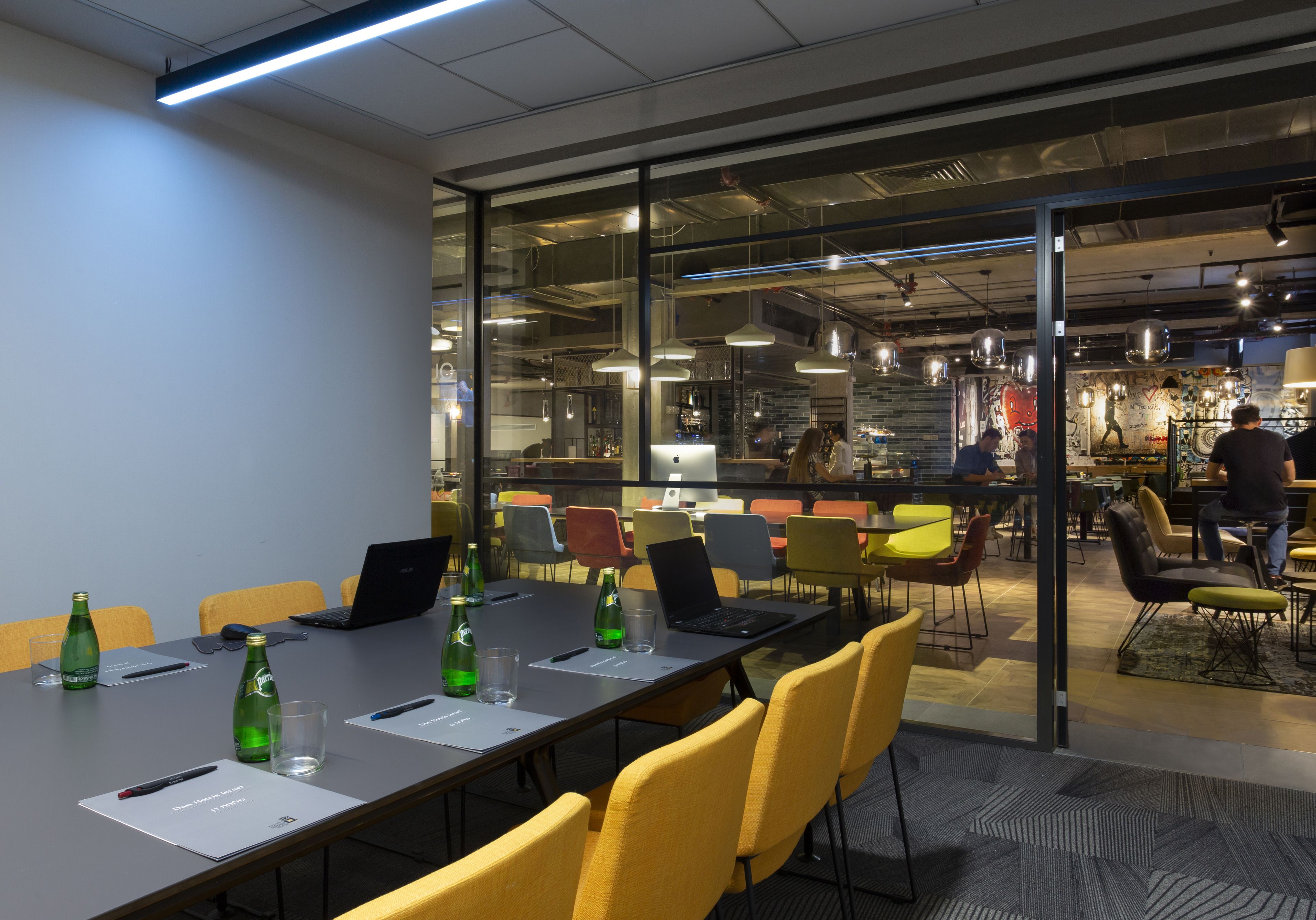 A modern conference room with a long table, chairs, and laptops.
