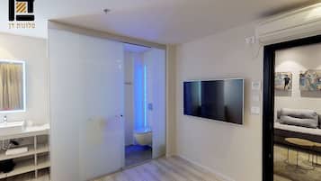 A modern living room with a flat-screen TV mounted on the wall, a sofa, and a coffee table.