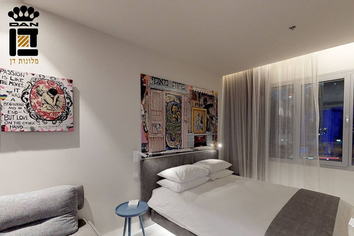 Ein modernes Schlafzimmer mit einem großen Bett, einem kleinen Nachttisch, einer Couch und Kunstwerken an den Wänden.