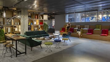 A modern lounge area with a green sofa, a wooden coffee table, and a variety of colorful chairs.