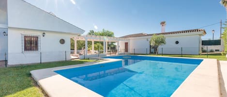 A swimming pool with a pergola and a covered patio area.