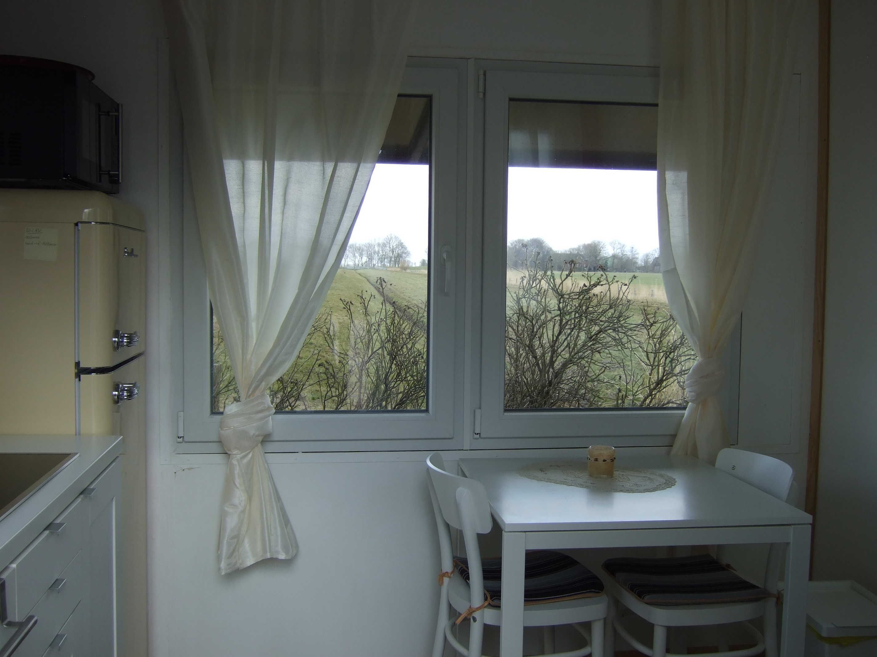 A room with a window, a table with chairs, and a kitchenette.