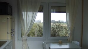 Una habitación con ventana, una mesa con sillas y una kitchenette.