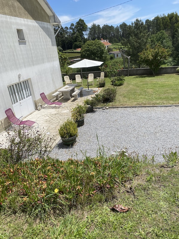 Un patio con mobiliario exterior, un pequeño jardín y vistas del paisaje circundante.