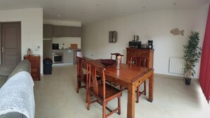 A living room with a sofa, TV, wooden coffee table, and a dining area with a table and chairs.