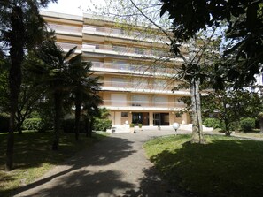 Ein mehrstöckiges Hotel mit Innenhof, umgeben von Bäumen und einem Weg zum Eingang.