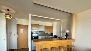 A modern kitchen with wooden cabinets, a central island with stools, and a visible oven.