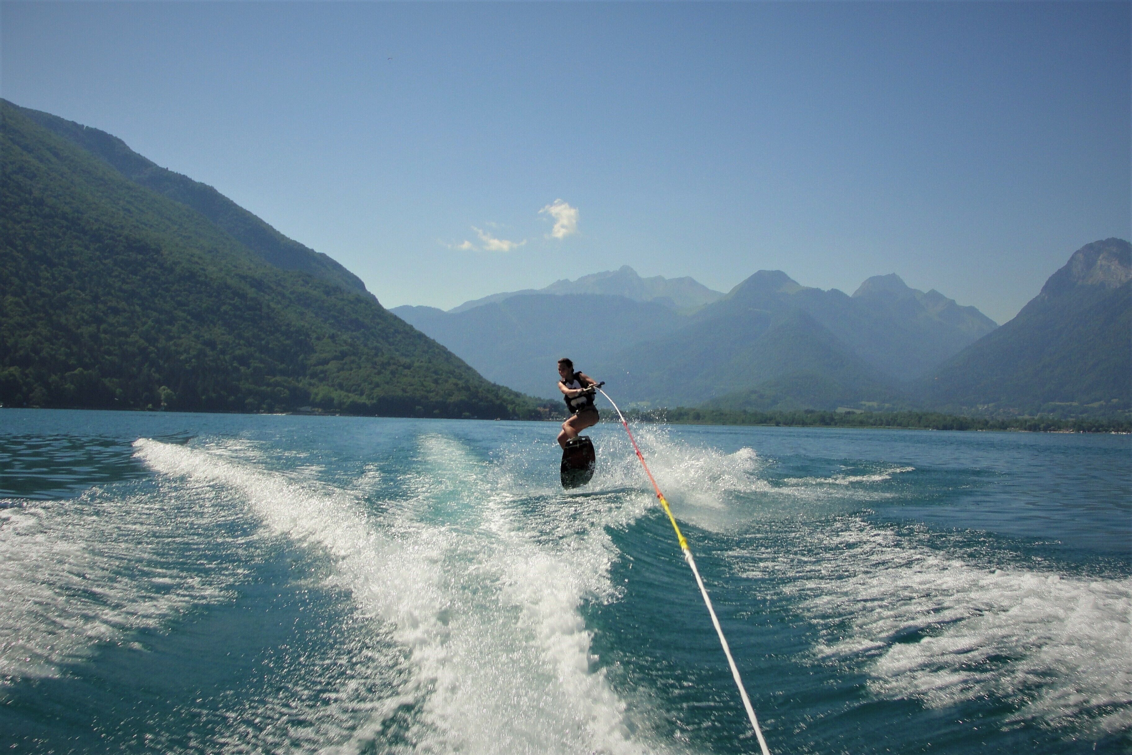 A person wakeboarding on a lake with mountains in the background.