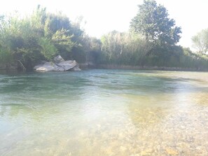 A river with clear water, surrounded by rocks and greenery.