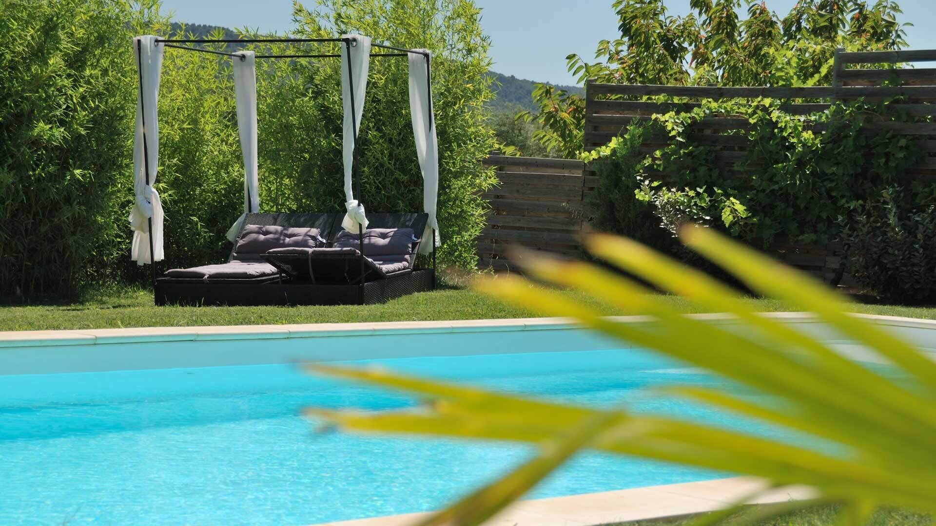 A swimming pool with a sun lounger and a pergola.