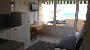 Une cuisine compacte avec un coin repas, un téléviseur et une vue sur la plage.