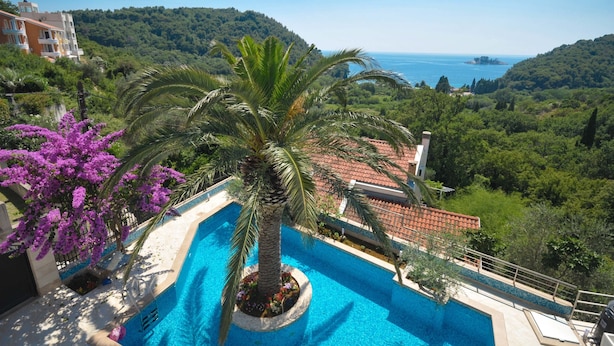 A swimming pool surrounded by lush greenery and a view of the sea. - St. George Apartments and Villa with pool (Petrovac)