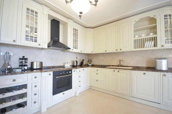 A kitchen with white cabinetry, a black range hood, and a marble countertop. - St. George Apartments and Villa with pool (Petrovac)