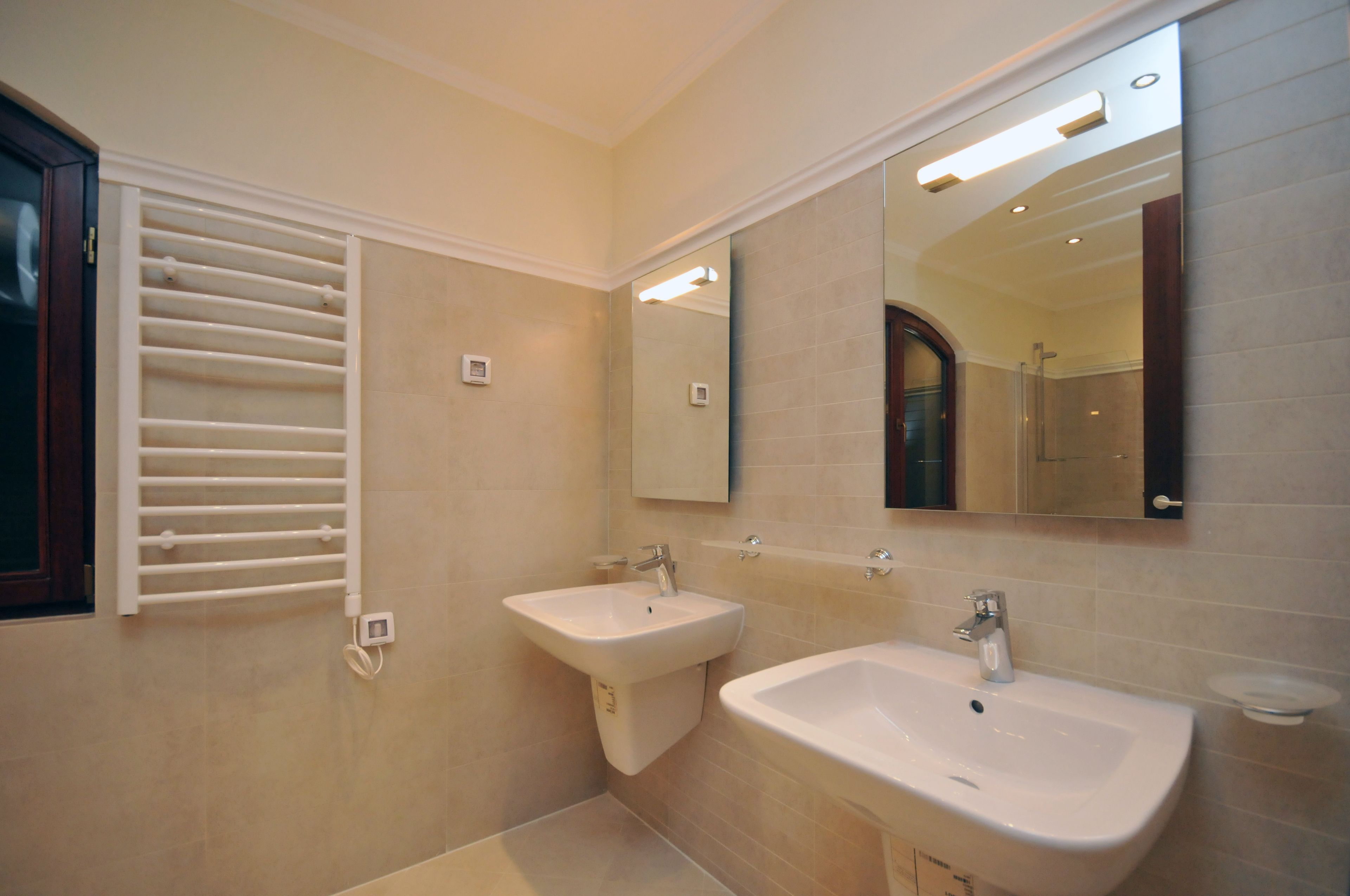 A modern bathroom with two sinks, a towel rack, and a large mirror.