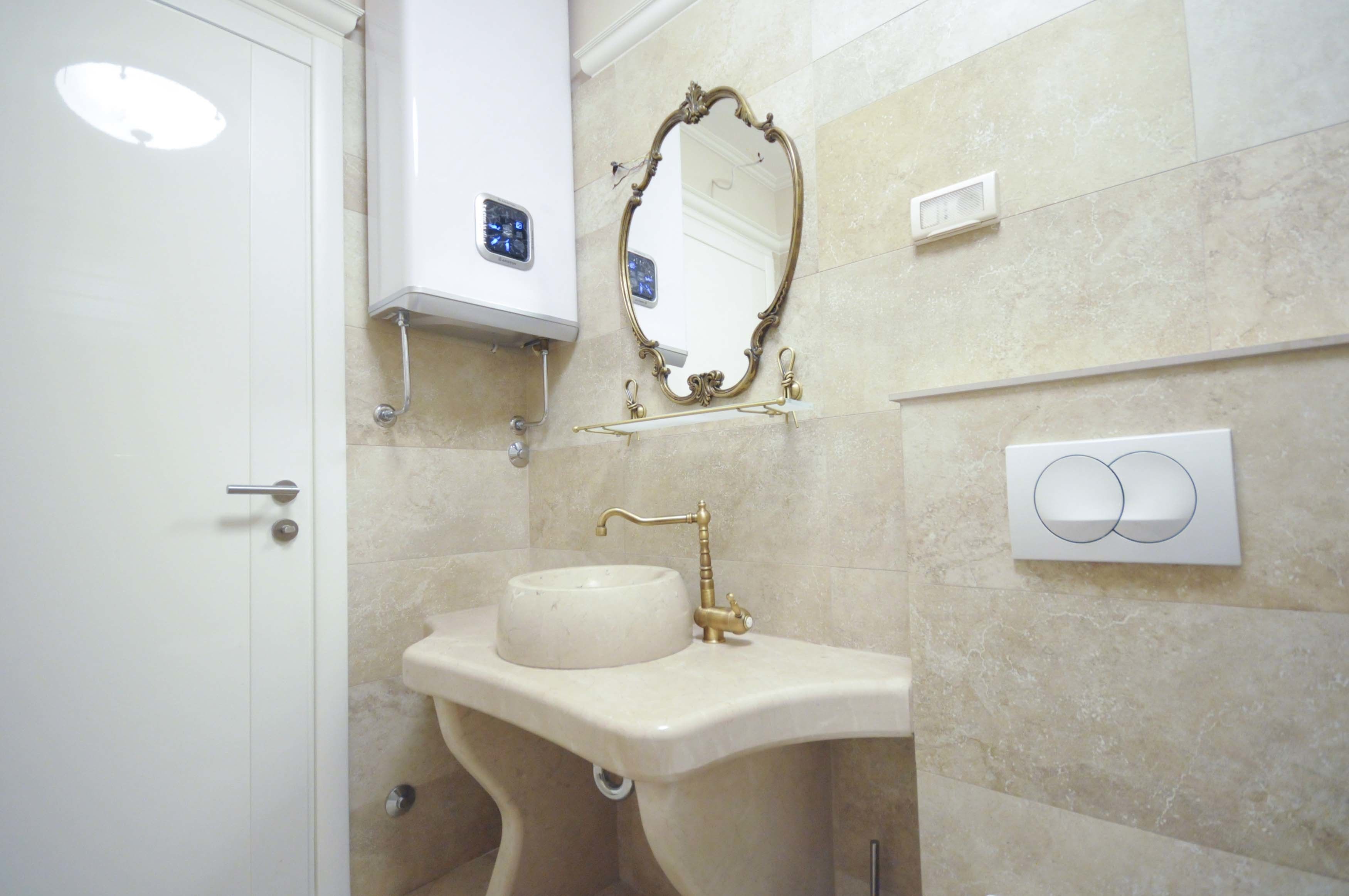 A bathroom with a pedestal sink, a wall-mounted mirror, and a toilet.