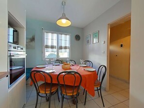 A dining area with a table set for six, chairs, a clock, and a window with blinds.