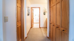 Un couloir avec des portes en bois, un plancher recouvert de moquette et un petit tapis.