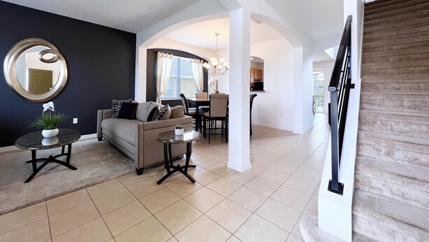 A modern living room with a sofa, coffee table, and a dining area with chairs and a table.