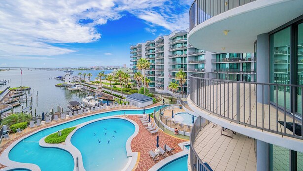 A modern hotel with a pool area, a marina, and a view of the water.
