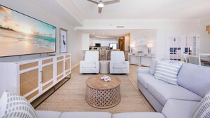 A spacious living room with a large flat-screen TV, white furniture, and a ceiling fan. - 9th Floor BEACH FRONT 3 Bedroom! Phoenix West LAZY RIVER (Orange Beach)