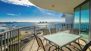 Un balcon avec une table et des chaises donnant sur un port de plaisance et sur le paysage urbain.