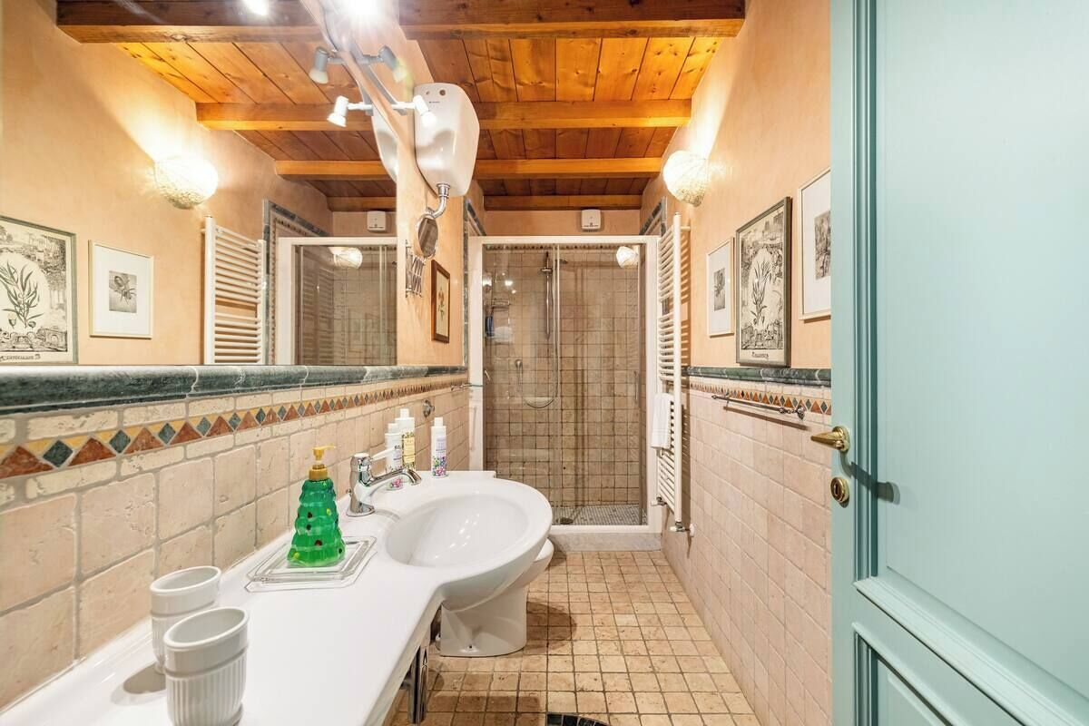 A bathroom with a wooden ceiling, a large sink, a shower, and decorative tiles.