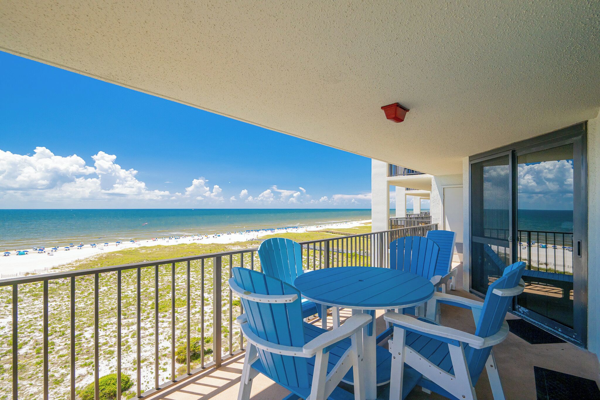 Un balcon avec vue sur la plage et l’océan, comprenant une table et des chaises.