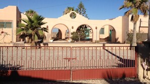 A building with a beige facade, arched entryways, and palm trees.