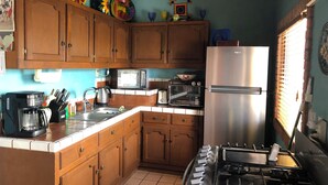 A kitchen with wooden cabinets, a stainless steel refrigerator, a gas stove, a microwave, and a coffee maker.