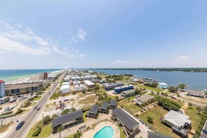 A coastal residential area with a large swimming pool, multiple buildings, and a clear view of the ocean.