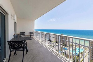 A balcony with a view of the ocean and a pool area.