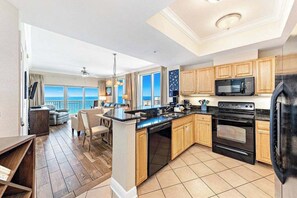 A modern kitchen with wooden cabinets, a black refrigerator, and a built-in oven.