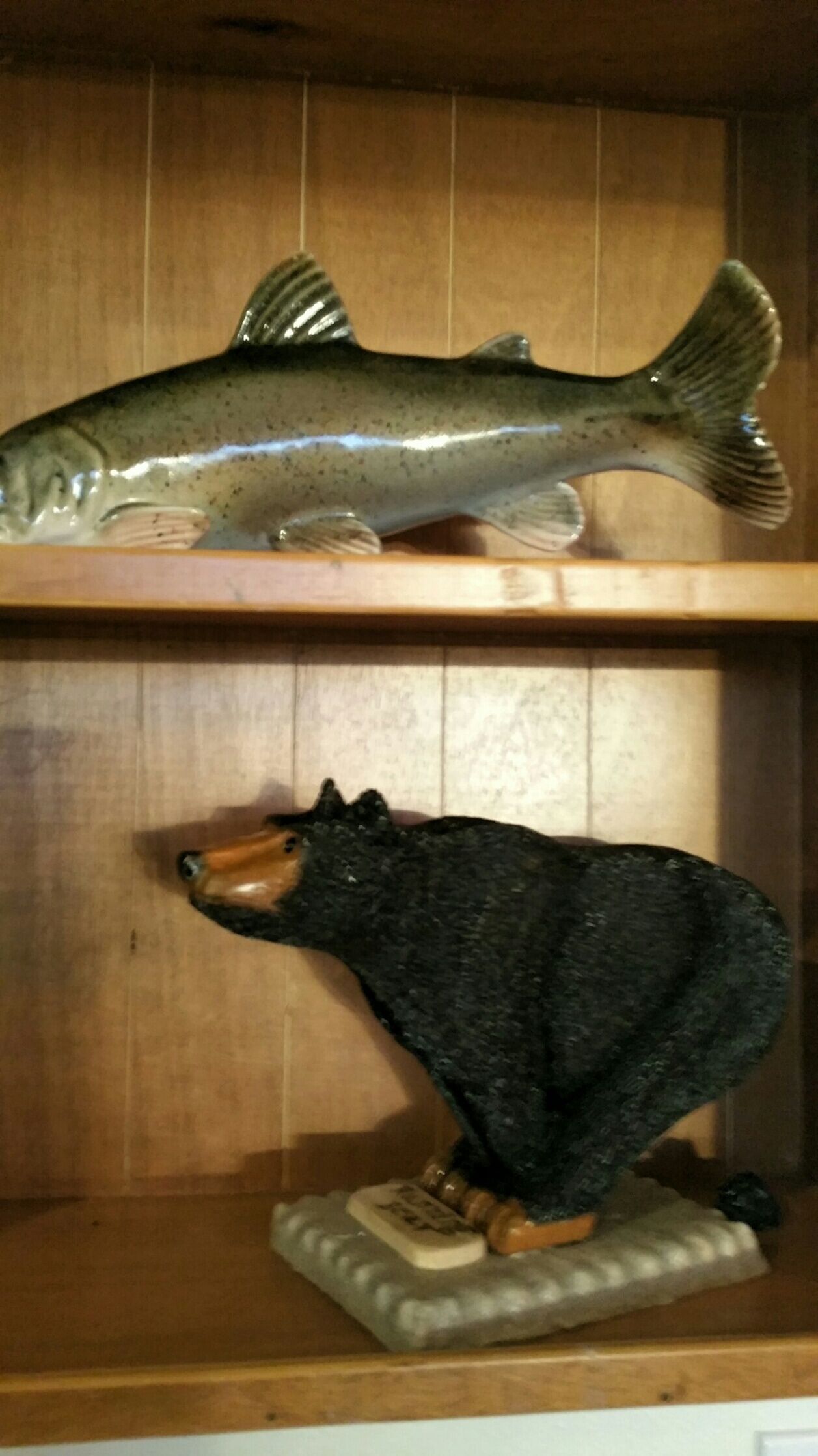 A wooden shelf with a fish and a bear figurine.