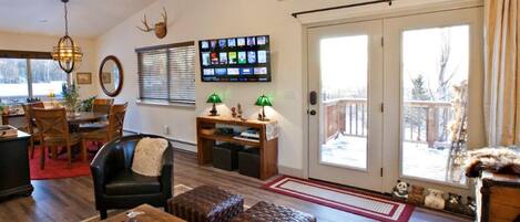 A cozy living room with a fireplace, a television mounted on the wall, and a sliding glass door leading to a deck.
