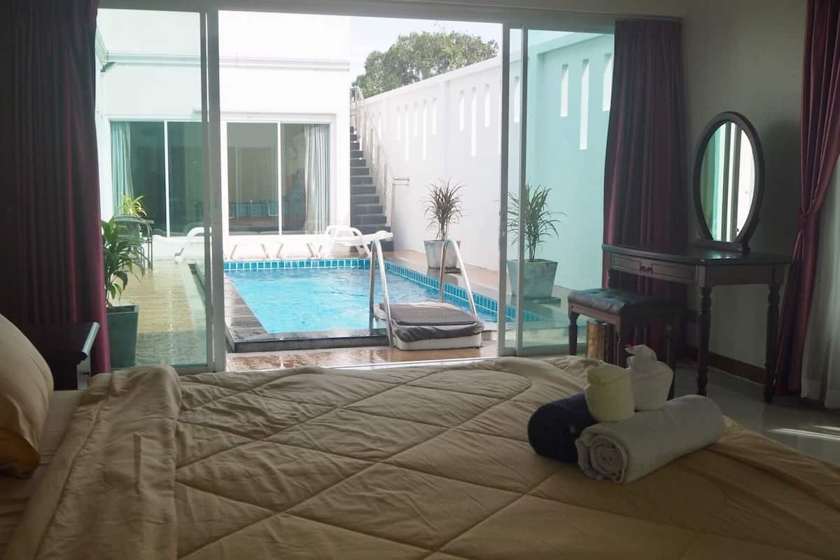 A hotel room with a large bed, a view of a swimming pool, and a staircase leading to an outdoor area.