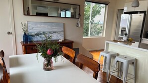Eine moderne Küche mit einem großen Fenster, einem Esstisch mit Blumen und einem Kühlschrank.