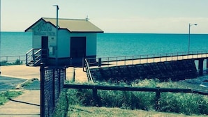 Ein kleines, eingeschossiges Gebäude mit einem Schild, auf dem 'Simmons Beach House & Cottages' steht.