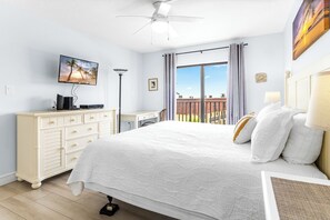 Ein Schlafzimmer mit Bett, Schminktisch, Schreibtisch, Fernseher und einem Balkon mit Blick.