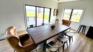 Ein Essbereich mit Holztisch und Ledersesseln, große Fenster mit Blick ins Freie.