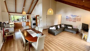 A spacious living area with a wooden dining table, a sofa, and a television. - 5 bedroom 2 bathroom family beach house with glimpses of Geographe Bay (Dunsborough)