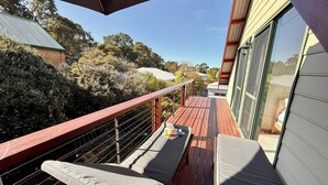 A balcony with wooden flooring, a metal railing, and two cushioned seating areas. - 5 bedroom 2 bathroom family beach house with glimpses of Geographe Bay (Dunsborough)
