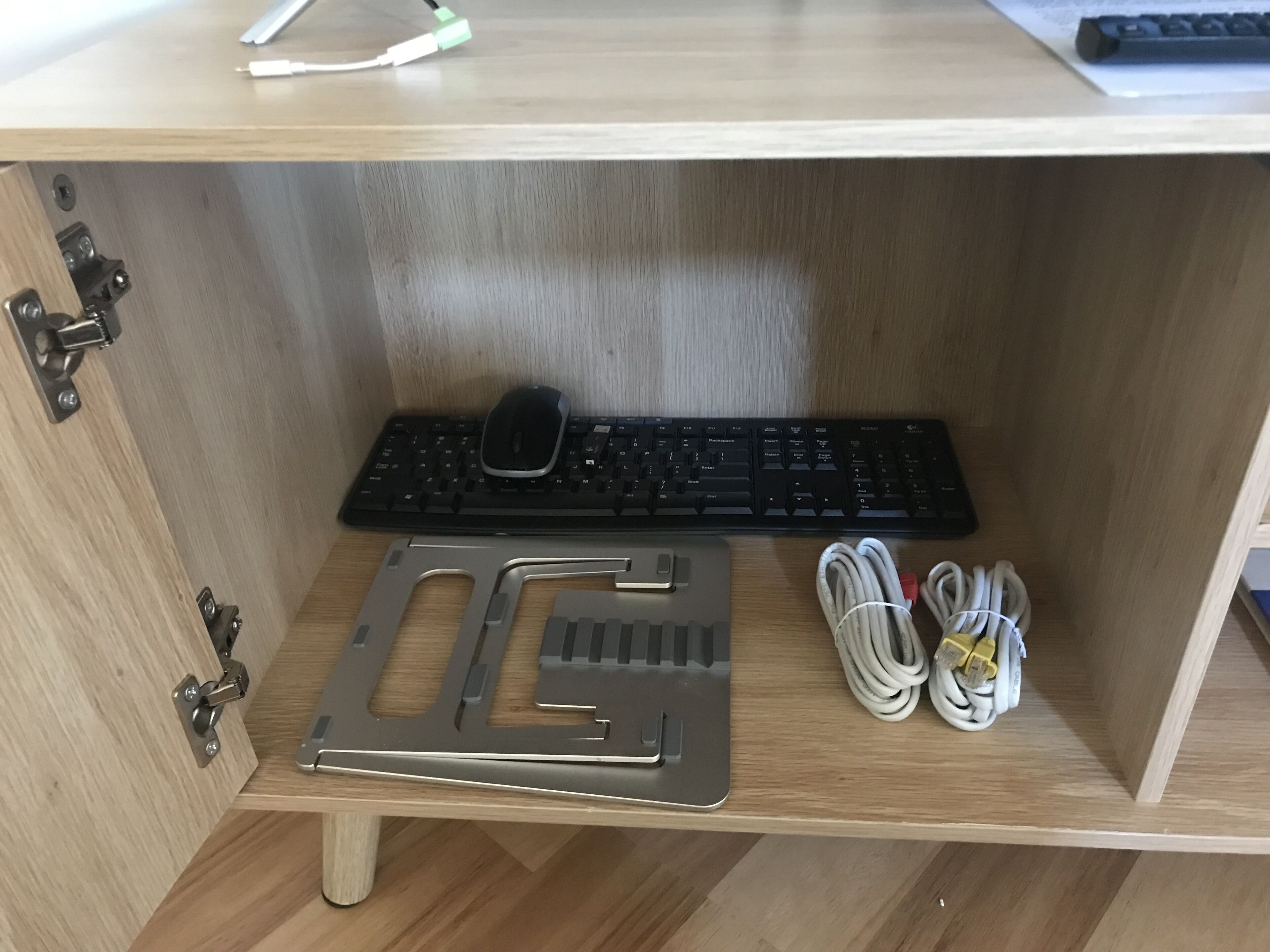 Un bureau en bois avec un clavier noir, une souris et des câbles enroulés.