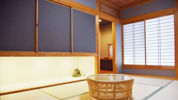 Ein Raum mit Tatami-Matten, einem Tatami-Tisch, einem Shoji-Bildschirm und traditioneller japanischer Einrichtung.