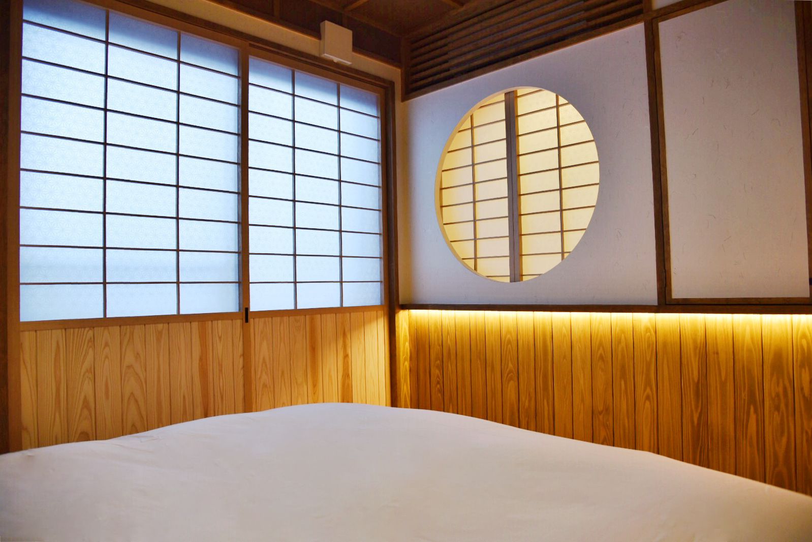 A traditional Japanese-style room with tatami flooring, shoji screens, and a circular window.