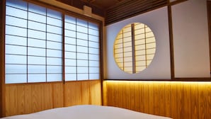 Ein traditioneller japanischer Raum mit Tatami-Böden, Shoji-Schirmwänden und einem runden Fenster.