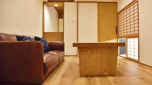 Ein Zimmer mit einer braunen Ledersofa, einem Holztisch und einem verschiebbaren Shoji-Bildschirm.